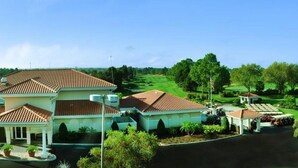 A large, two-story house with a tiled roof, a covered patio, and a well-maintained lawn. - Ref 415. Stunning villa with golf course view. South pool. (Haines City)