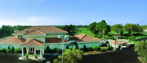 A large, two-story house with a tiled roof, a covered patio, and a well-maintained lawn.