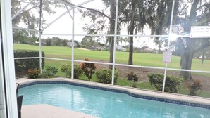 A pool with a view of a golf course through a covered area. - Ref 415. Stunning villa with golf course view. South pool. (Haines City)