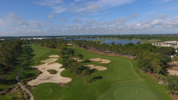 An aerial view of a golf course with sand bunkers, a water body in the background, and a clear sky. - Ref 415. Stunning villa with golf course view. South pool. (Haines City)