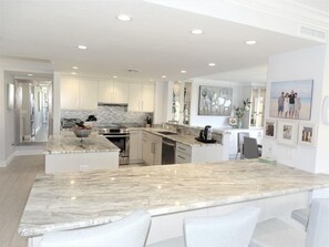 A modern kitchen with white cabinetry, a marble countertop, and stainless steel appliances.