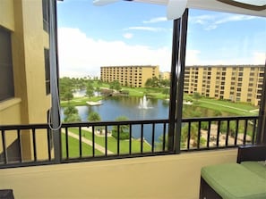 Un balcón con vistas a un complejo hotelero, un estanque y un campo de golf.