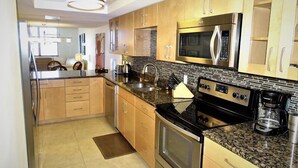 A modern kitchen with stainless steel appliances, wooden cabinets, and a granite countertop. - Gulf and Bay Club- B608 Beautiful and great view! (Siesta Key)