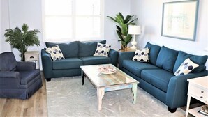 Un salon avec deux canapés, une table basse, une table d’appoint et une lampe.