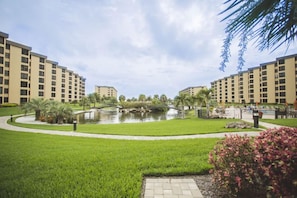 A hotel courtyard with a central pond, surrounded by well-maintained grass and palm trees. - Gulf and Bay Club C105: Siesta Key Condo with Direct Pool and Beach Access! (Siesta Key)