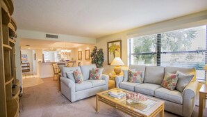 A spacious living room with a light-colored sofa set, a coffee table, and a dining area in the background. - Gulf and Bay Club- C201 Beautiful updates! (Siesta Key)