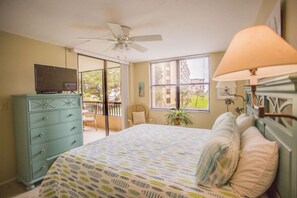 A bedroom with a bed, a dresser, a ceiling fan, a window with blinds, and a balcony. - Gulf and Bay Club- C202 Amazing kitchen! (Siesta Key)