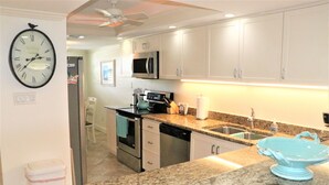 A kitchen with white cabinets, a microwave, a stove, and a sink. - Gulf and Bay Club- C305 (Siesta Key)