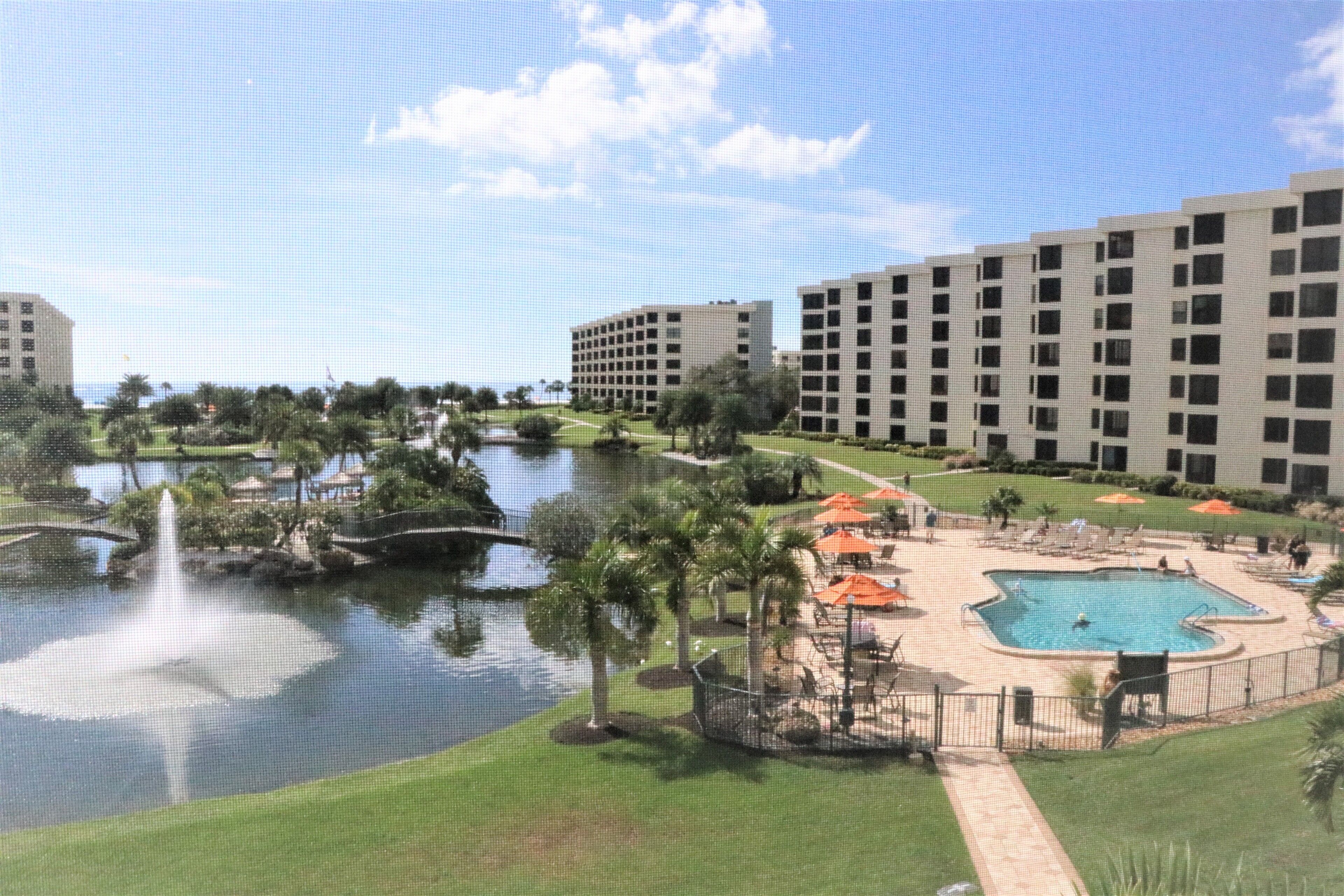 A hotel with multiple buildings, a swimming pool, and a fountain.
