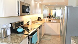 Una cucina moderna con mobili bianchi, elettrodomestici in acciaio inossidabile e piani in granito.