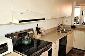A compact kitchen with a microwave, stove, and sink.