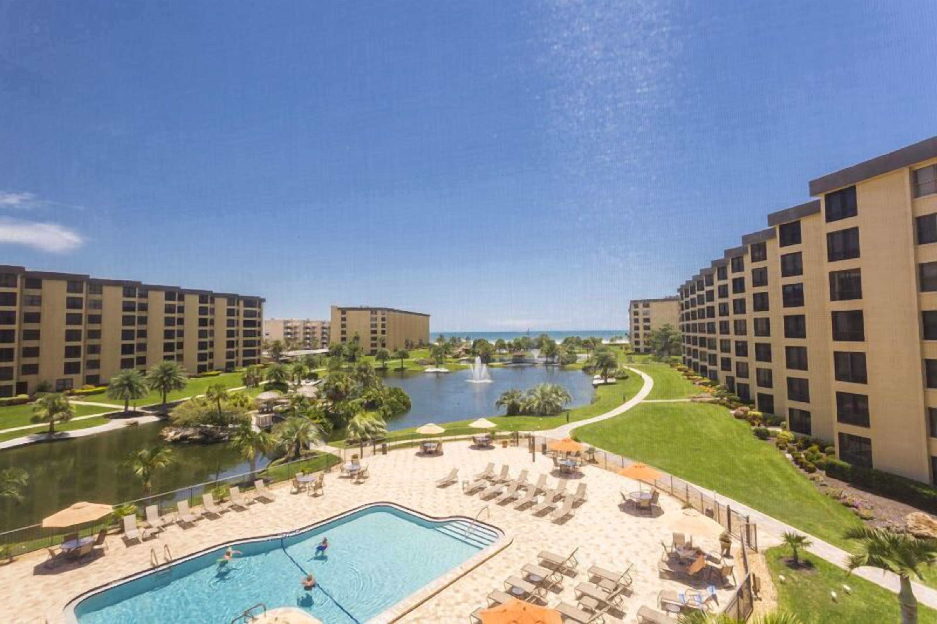 A hotel with a swimming pool, a fountain, and a view of the ocean.