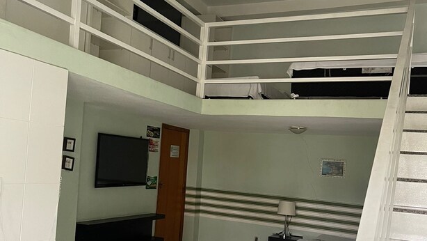 Un dormitorio con literas, un televisor, un escritorio y una escalera.
