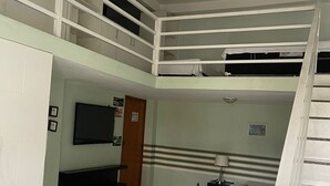 Un dormitorio con literas, un televisor, un escritorio y una escalera.