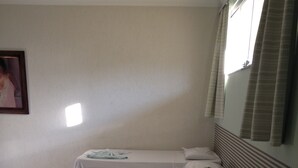 Habitación de hotel con cuatro camas individuales, cada una con una almohada y una toalla doblada con pulcritud.