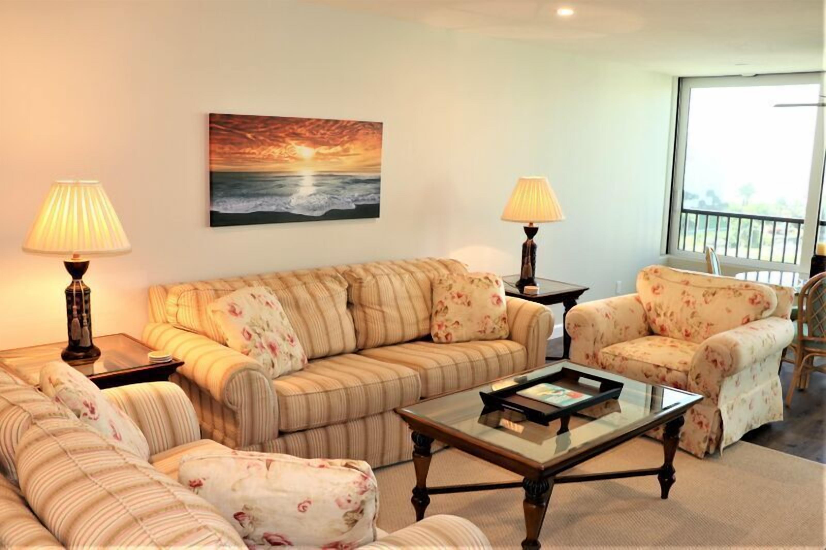 A living room with a sofa, armchairs, a coffee table, and two lamps.