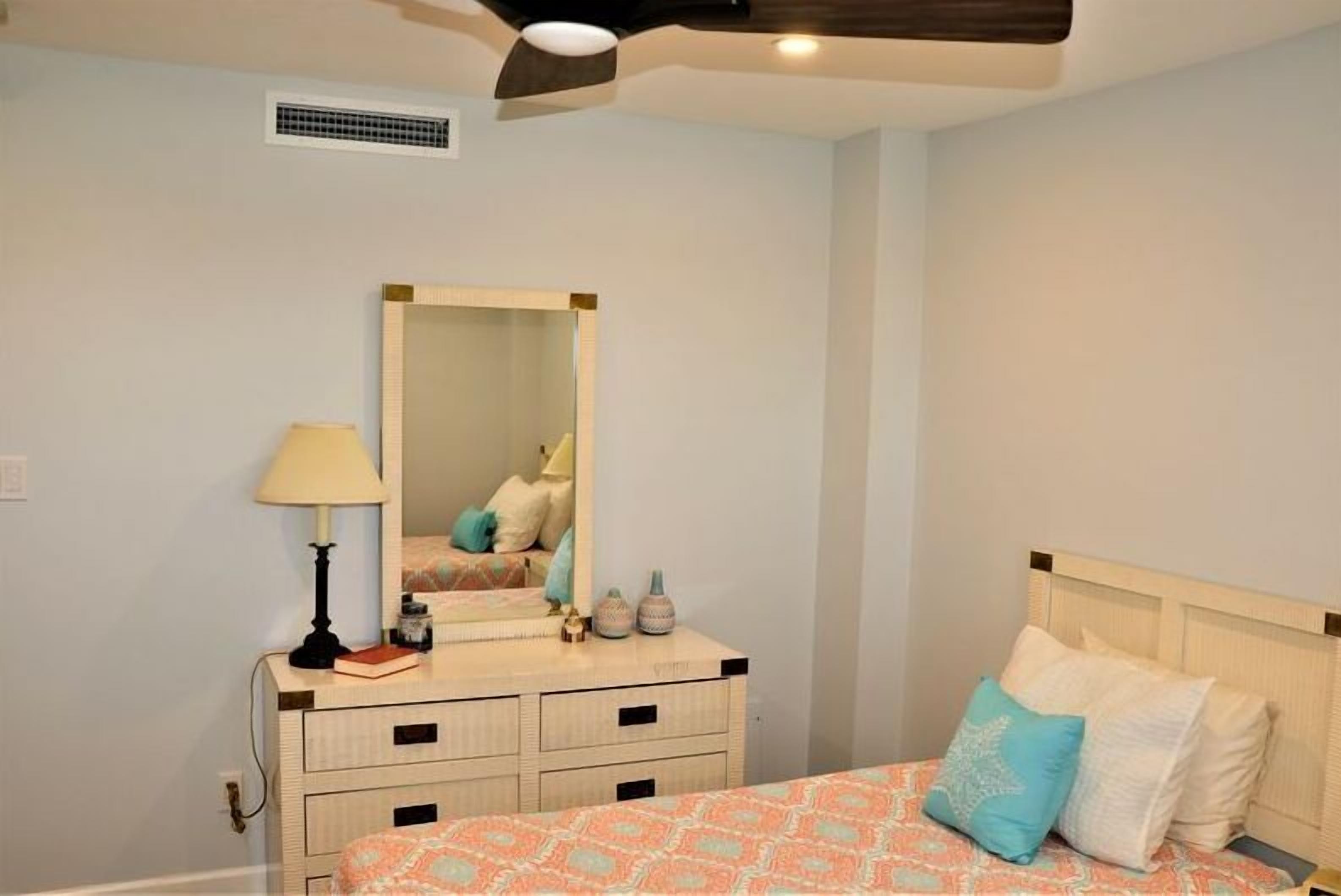 A bedroom with a bed, a dresser, a mirror, and a lamp.
