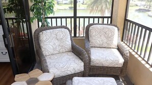 A balcony with wicker chairs and a wooden table. - Gulf and Bay Club- D209 (Siesta Key)