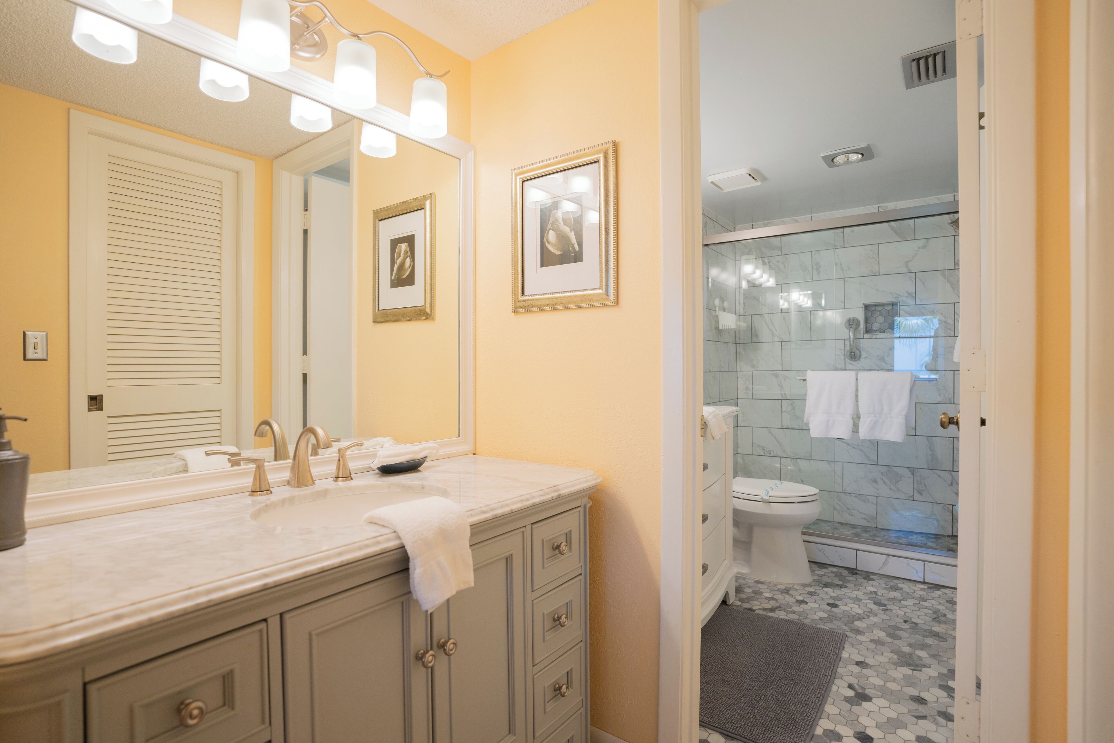 A bathroom with a double sink vanity, a large mirror, and a shower area.