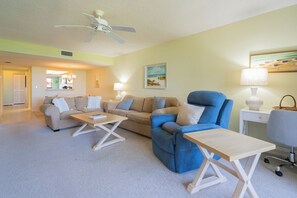 A living room with a ceiling fan, two sofas, a coffee table, and a desk with a chair.