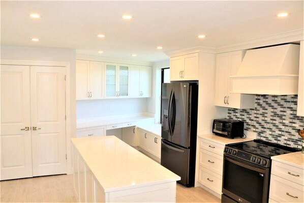 A modern kitchen with white cabinetry, a black refrigerator, a microwave, and an oven.