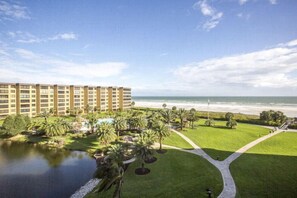 A hotel with a pool, palm trees, and a view of the beach. - Gulf and Bay Club- E505 Spectacular views! (Siesta Key)