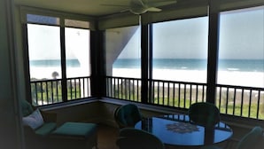 Una veranda con vista sull'oceano, una ventola a soffitto e un tavolo rotondo con sedie.