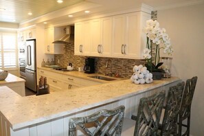 A modern kitchen with white cabinets, a granite countertop, and a central island with bar stools.