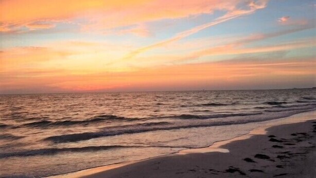 A beach with a sunset, waves, and footprints in the sand. - Gulf Holiday Unit 12- Close to Beach and Siesta Key Village! (Siesta Key)