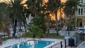 A swimming pool with a fence, lounge chairs, and palm trees. - Gulf Holiday Unit 12- Close to Beach and Siesta Key Village! (Siesta Key)