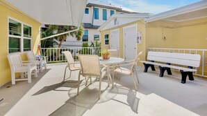 Une terrasse extérieure ensoleillée avec une table ronde, des chaises et un banc.