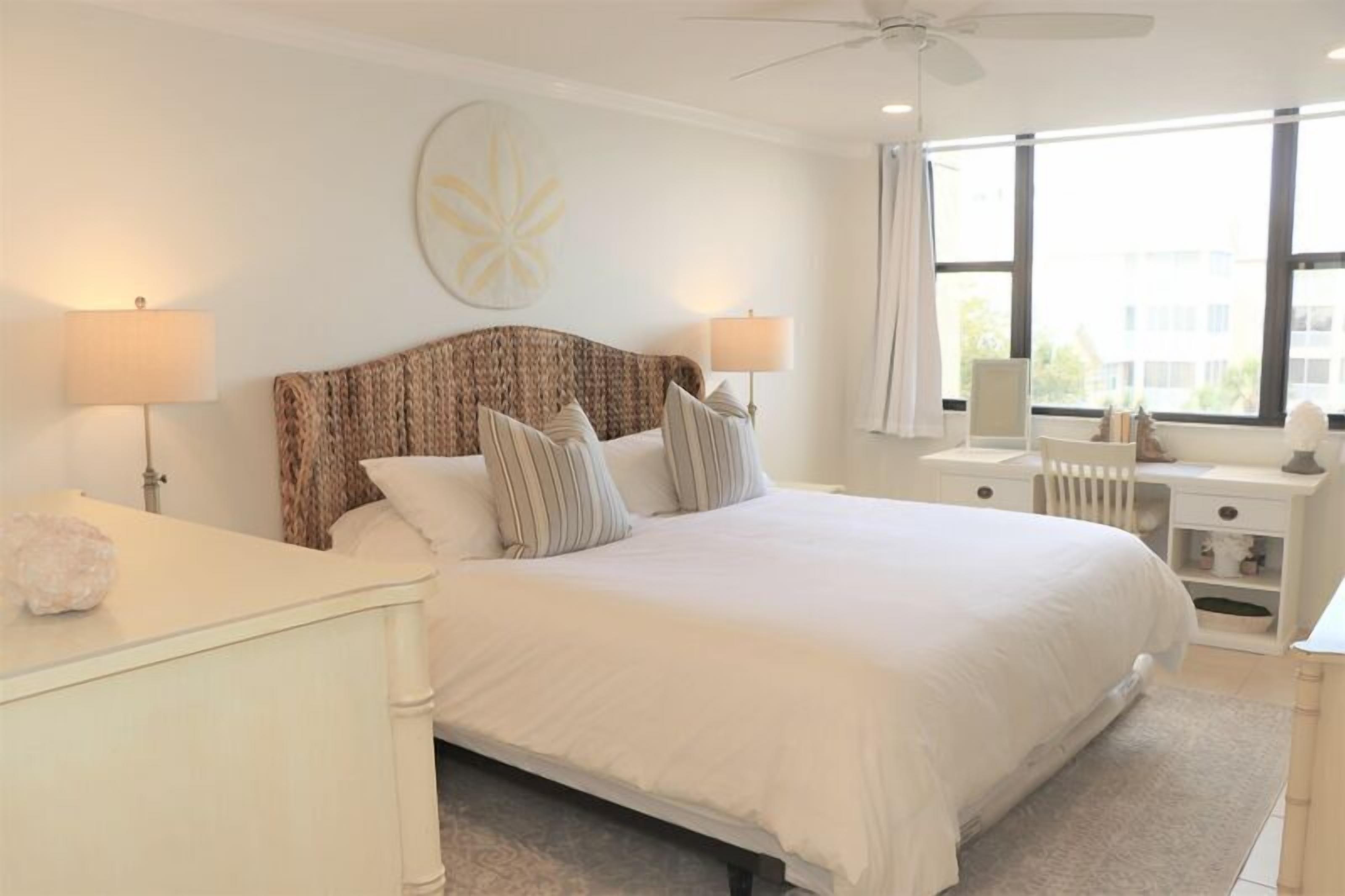 A neatly arranged bedroom with a large bed, two bedside tables, a radiator, and a window with a view.