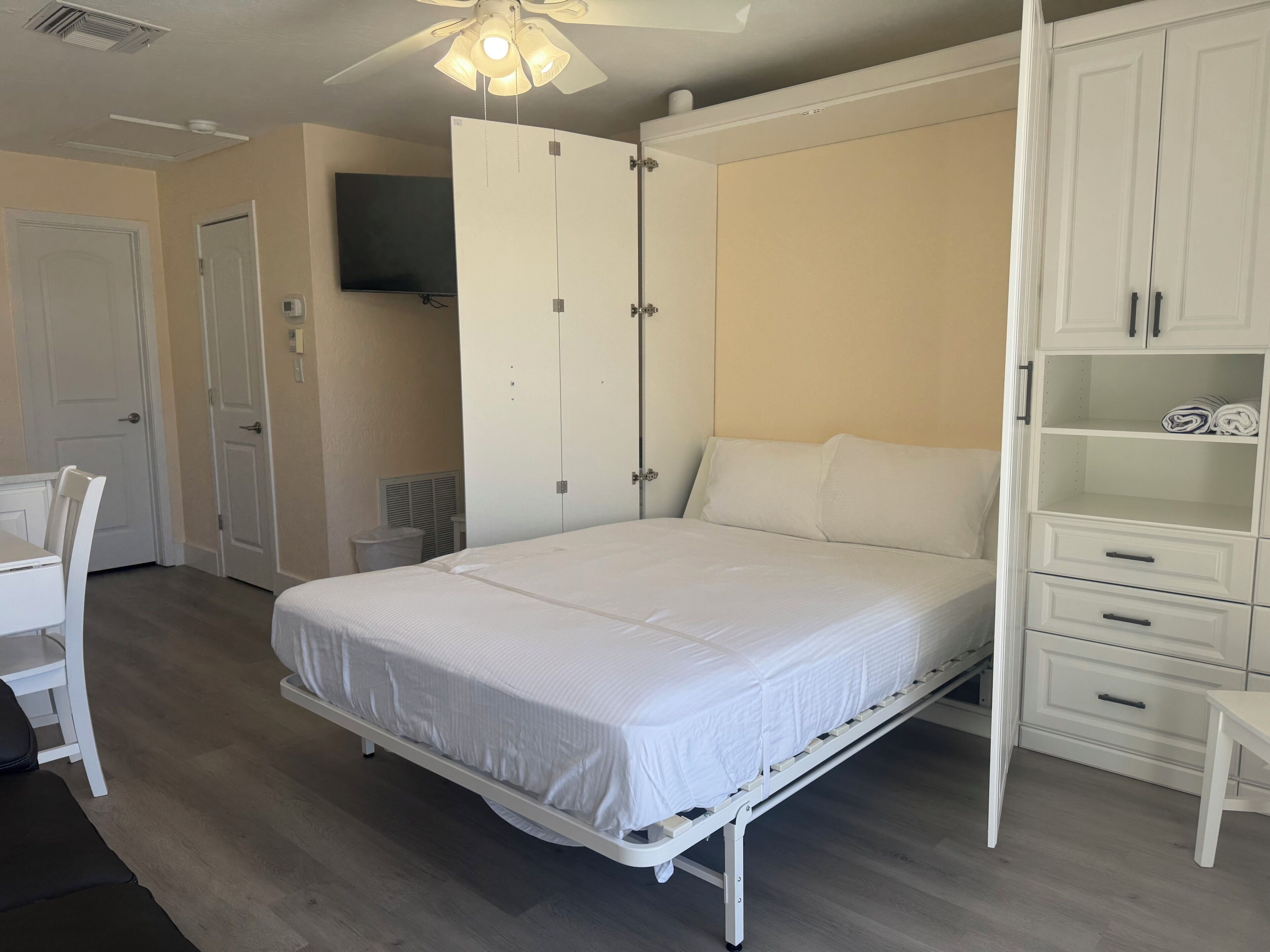 Ein Schlafzimmer mit Bett, Kleiderschrank, Fernseher und Deckenventilator.