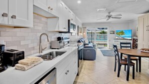 A modern kitchen with white cabinets, a built-in oven, and a dining area with a table and chairs. - Jamaica Royale 009 Updated and across from pool! (Siesta Key)