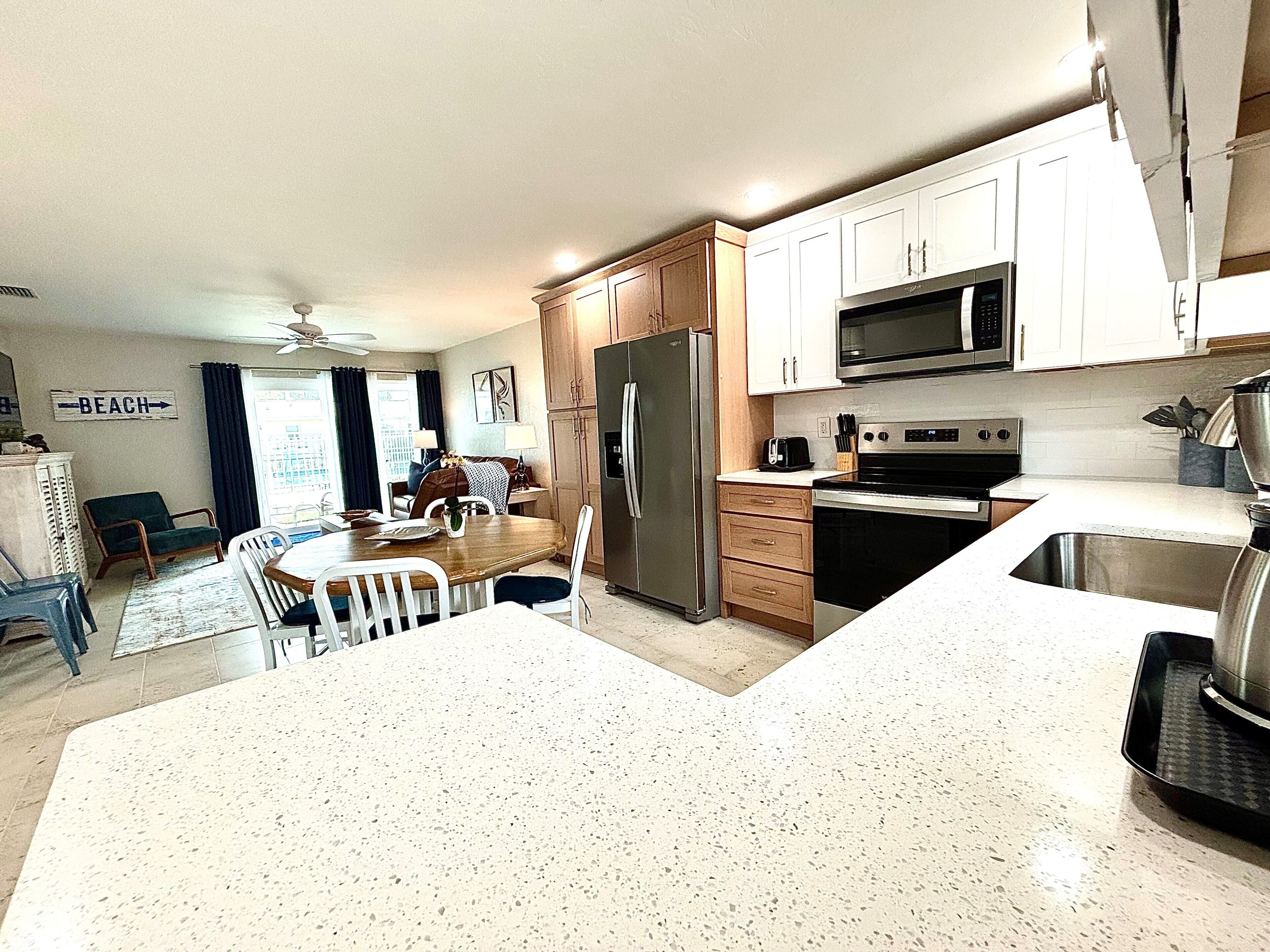A modern kitchen with white cabinetry, stainless steel appliances, and a dining area with a table and chairs.