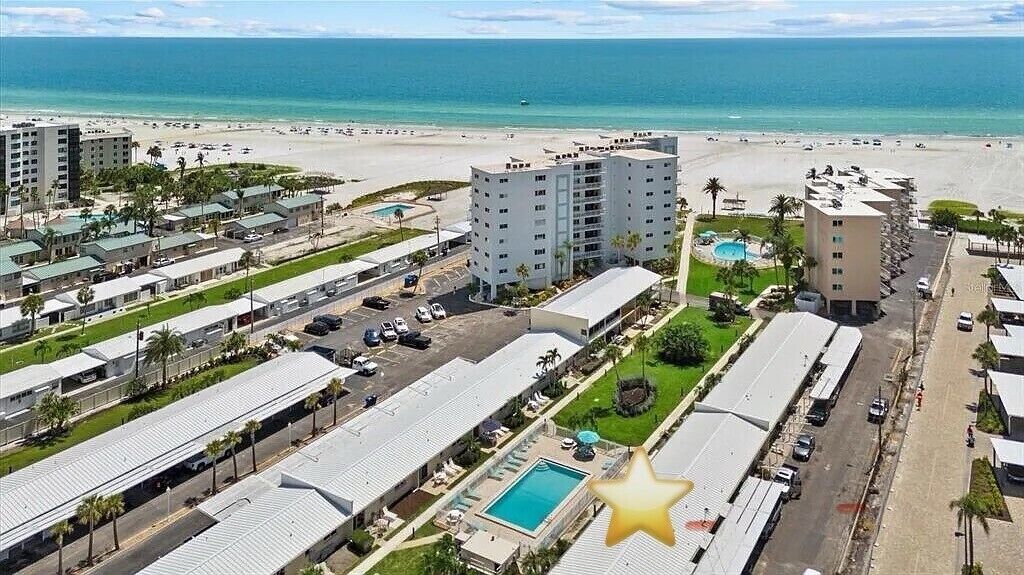 A beachfront hotel with multiple buildings, a swimming pool, and a beach view.