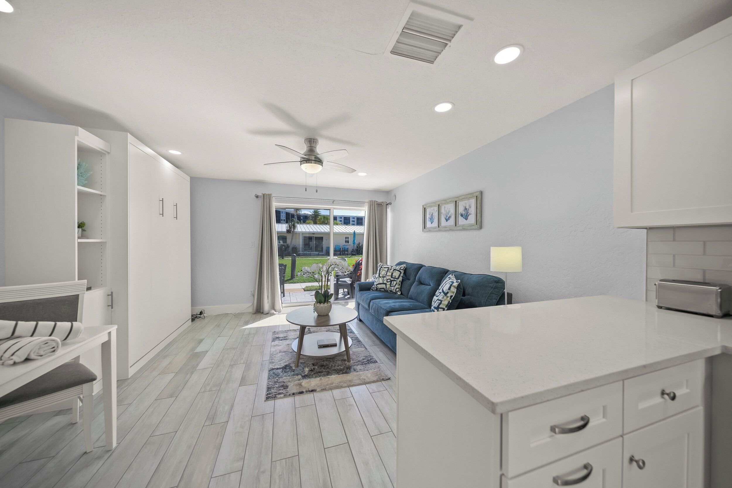 A modern living room with a sofa, a coffee table, and a dining area with a counter.