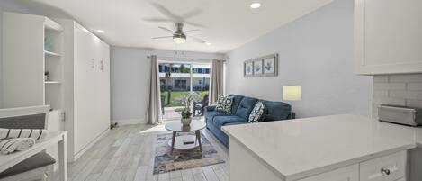 A modern living room with a sofa, a coffee table, and a dining area with a counter.