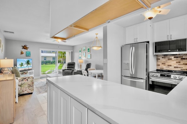 A modern kitchen with a large island, stainless steel appliances, and a view to the outdoors.