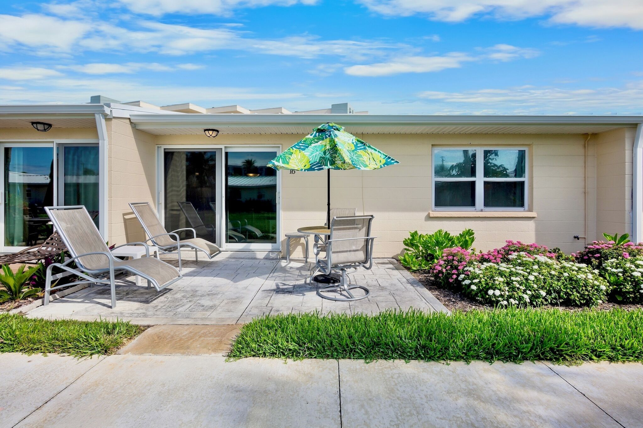 A house with a patio, outdoor furniture, and a large umbrella.