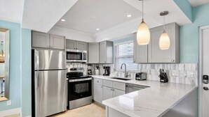 A modern kitchen with stainless steel appliances, a marble countertop, and pendant lighting. - Jamaica Royale 022 Short walk to the beach! (Siesta Key)