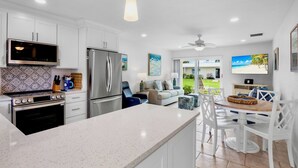 A modern kitchen with white cabinetry, stainless steel appliances, and a central island with seating. - Jamaica Royale 030 Nicely Updated! (Siesta Key)