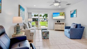 A living room with a sofa, a blue armchair, a coffee table, and a TV. - Jamaica Royale 030 Nicely Updated! (Siesta Key)