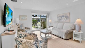 A modern living room with a sofa, armchairs, a coffee table, and a TV. - Jamaica Royale 033 Close to pool! (Siesta Key)