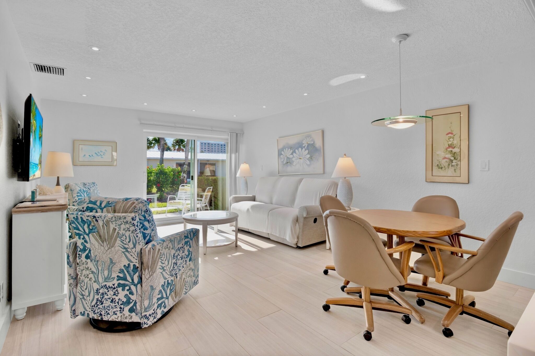A modern living room with a sofa, a dining table with chairs, a TV, and artwork on the walls.