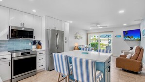 A modern kitchen with white cabinets, stainless steel appliances, and a blue tiled backsplash. - Jamaica Royale 048 Updated and close to the pool! (Siesta Key)