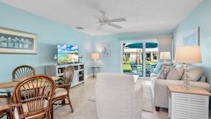 A living room with a dining area, a ceiling fan, a TV, and a view of the outdoors. - Jamaica Royale 051 Updated and close to the pool! (Siesta Key)