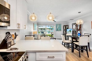 Una cucina moderna con mobili bianchi, un'isola centrale e lampade a cestino appese.