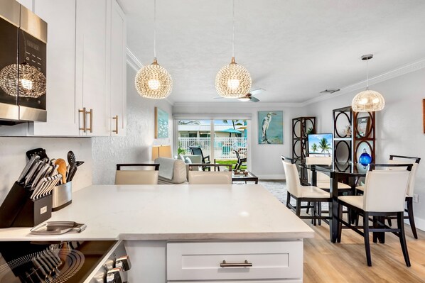 Una cocina moderna con armarios blancos, una isla central y lámparas colgantes de mimbre.