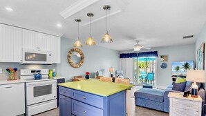 Une cuisine moderne avec des meubles blancs, un îlot central bleu et des luminaires suspendus.